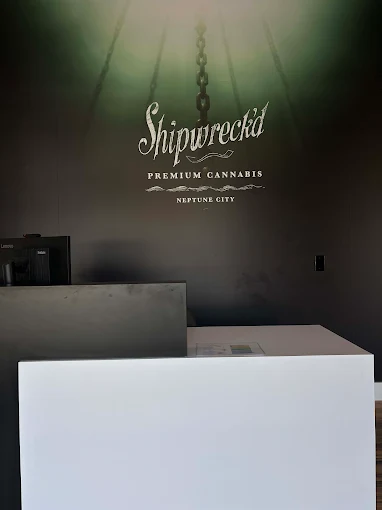 Shipwreck’d Premium Cannabis logo on wall, modern interior design, inviting atmosphere for Neptune City dispensary.